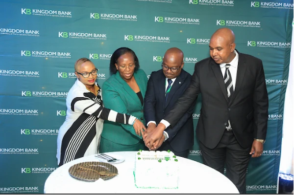  
Marion Ndungu (left) and Mary Wambugu (2nd left) join Edward Njoroge, Branch Manager of Kingdom Bank's Gikomba Branch (2nd right) and Alex Kasiki, Head of Business Development at Kingdom Bank, in cutting a cake during the official opening of the bank's 20th branch in Gikomba.